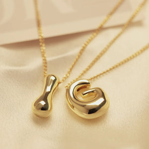 Bold Bubble Initial Pendant Necklace Gold I and G pendants close up on beige fabric