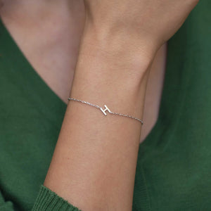 Silver initial bracelet with a single letter H worn on the wrist