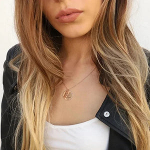 Rose gold handwriting disc necklace worn on the neck with a leather jacket