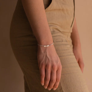 Silver capital letter name bracelet with the name RILEY worn on the wrist