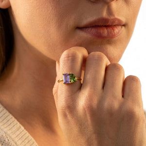 Gold You & Me double birthstone ring with purple and green stones worn on the finger