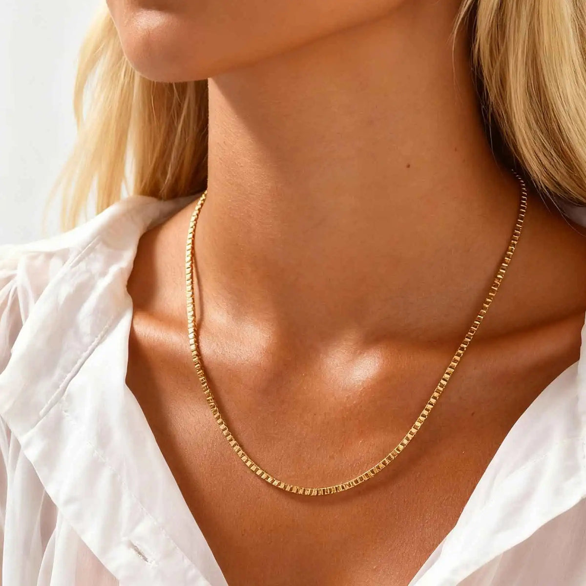Gold box chain necklace worn by a woman in a white shirt