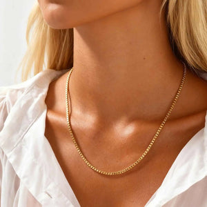 Gold box chain necklace worn by a woman in a white shirt