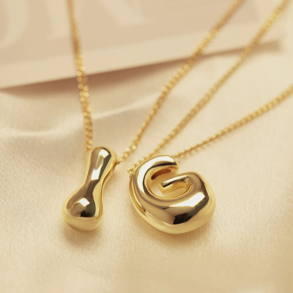 Bold Bubble Initial Pendant Necklace Gold I and G pendants close up on beige fabric
