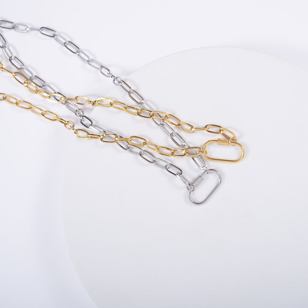 Gold and silver paperclip chains with oval carabiners on a white plate