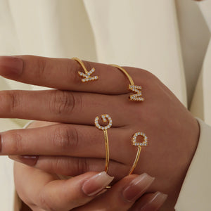 Gold initial cuffs with the letters K, M, G and D worn on the fingers