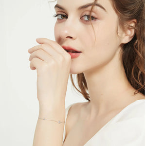 Dainty initial bracelet worn on the wrist, hand raised to the face