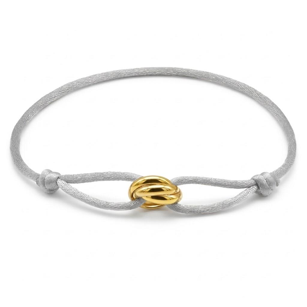 Bracelet with a gold knot design on a gray cord against a white background