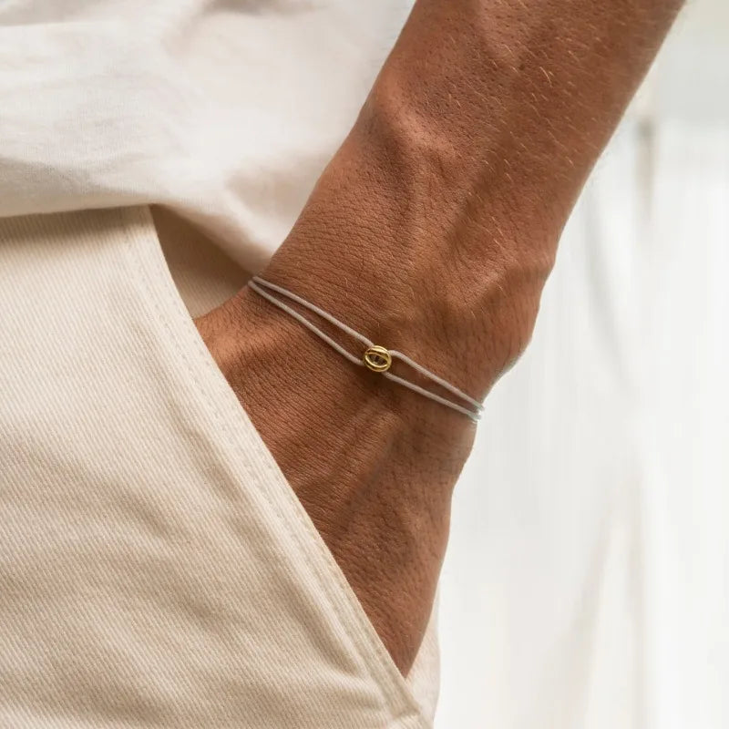 Grey Cord Infinity Bracelet with Gold Ring on Wrist
