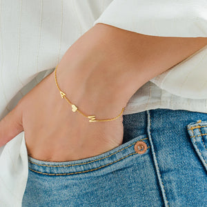 Gold multiple initials bracelet A and M with heart worn on the wrist