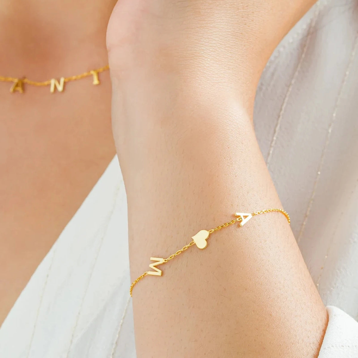 Gold initials bracelet A and M with heart, worn with a matching necklace