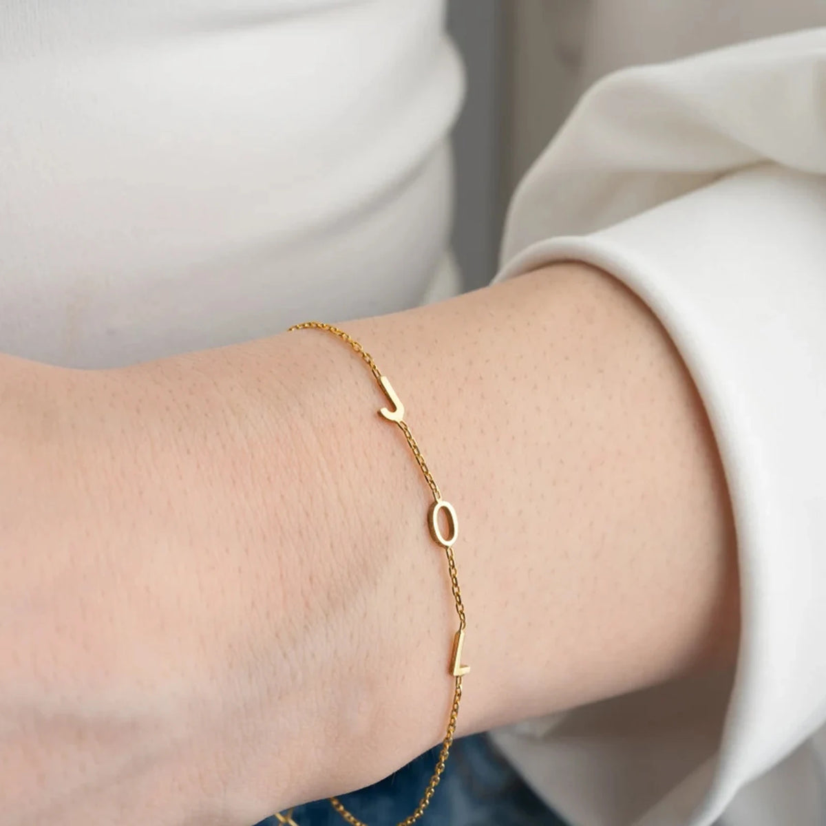 Gold multiple initials bracelet with three letters worn on the wrist
