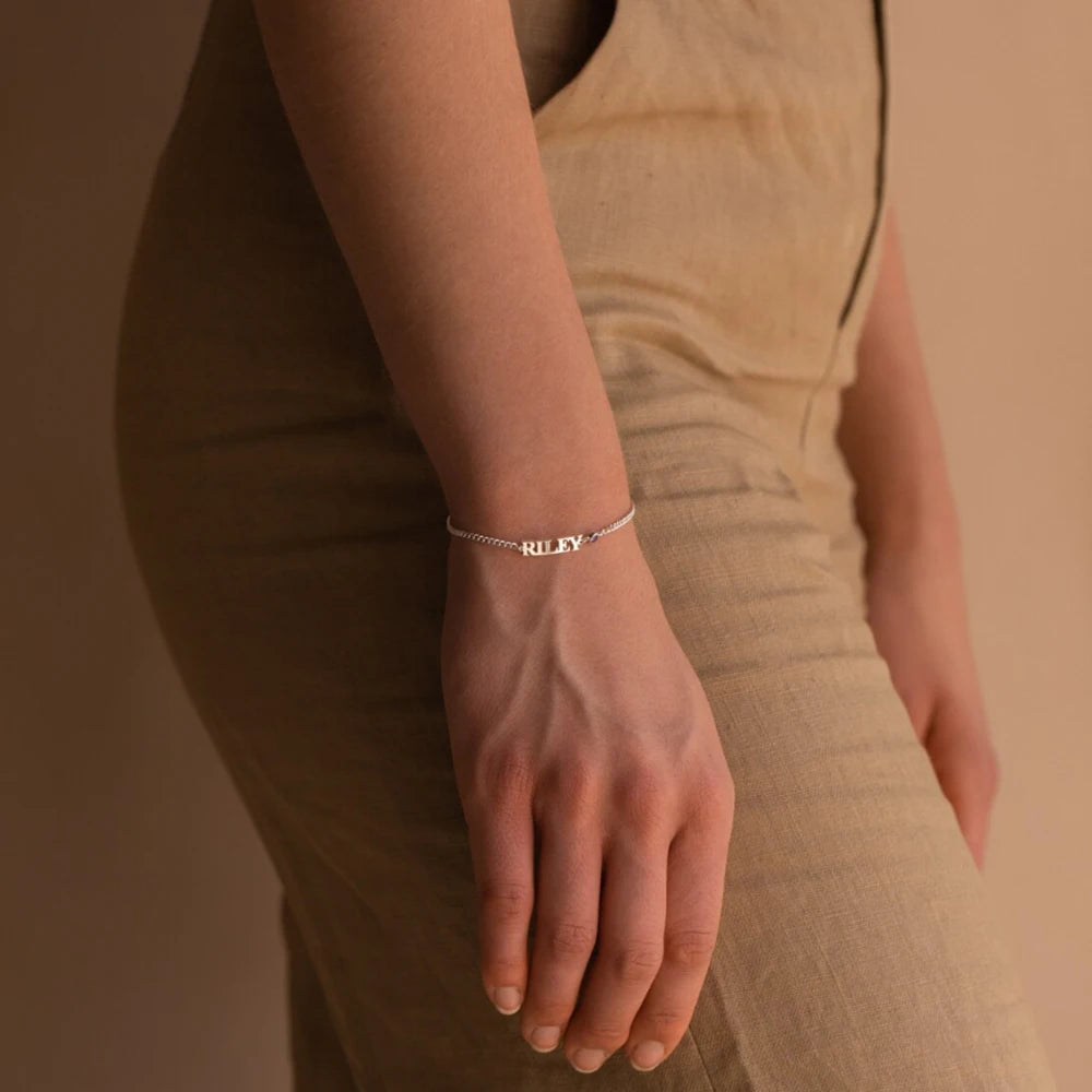 Silver capital letter name bracelet with the name RILEY worn on the wrist, side view