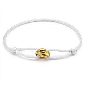 White bracelet with a gold knot charm on a white background