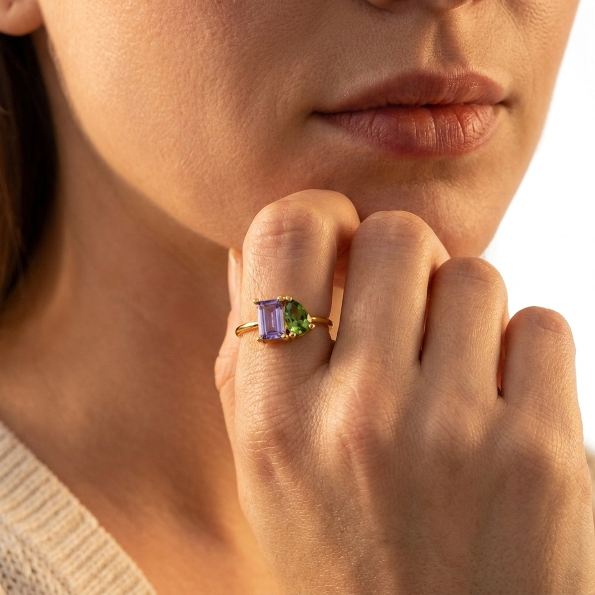 Gold You & Me double birthstone ring with purple and green stones worn on the finger